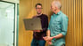 Two people talking in the hall way with laptop